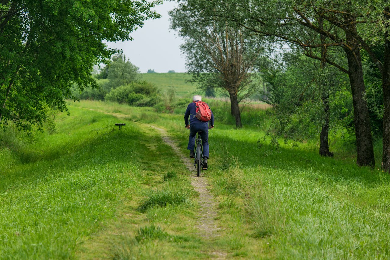 An adult cyclist rides through a lush green path in a rural forest area.